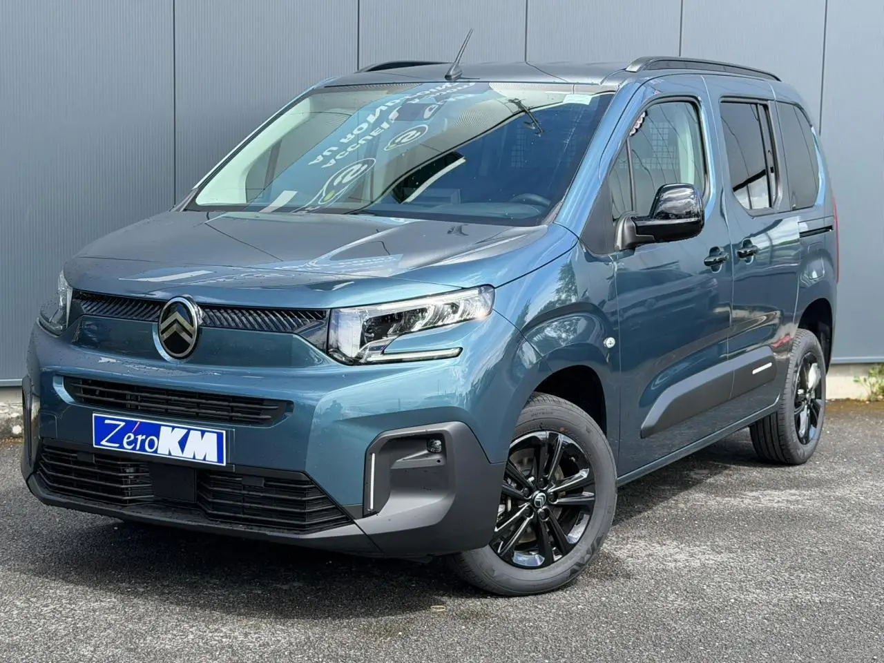Vue 3/4 avant droite du Citroën Berlingo Multispace 2026 bleu Kiama avec jantes alliage noires et barres de toit.