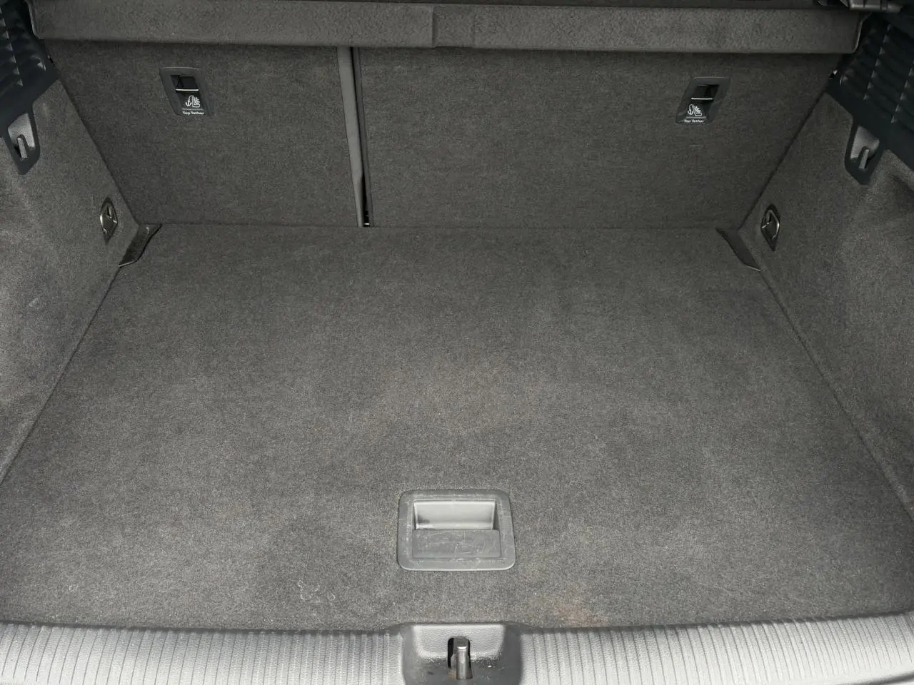 Vue intérieure du coffre spacieux et tapissé de moquette grise de l'Audi Q2 30 TFSI 110 S-Line 2024.