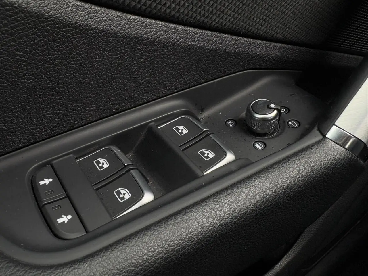 Gros plan sur les commandes de lève-vitres et réglage des rétroviseurs côté conducteur de l'Audi Q2 30 TFSI blanc Glacier.