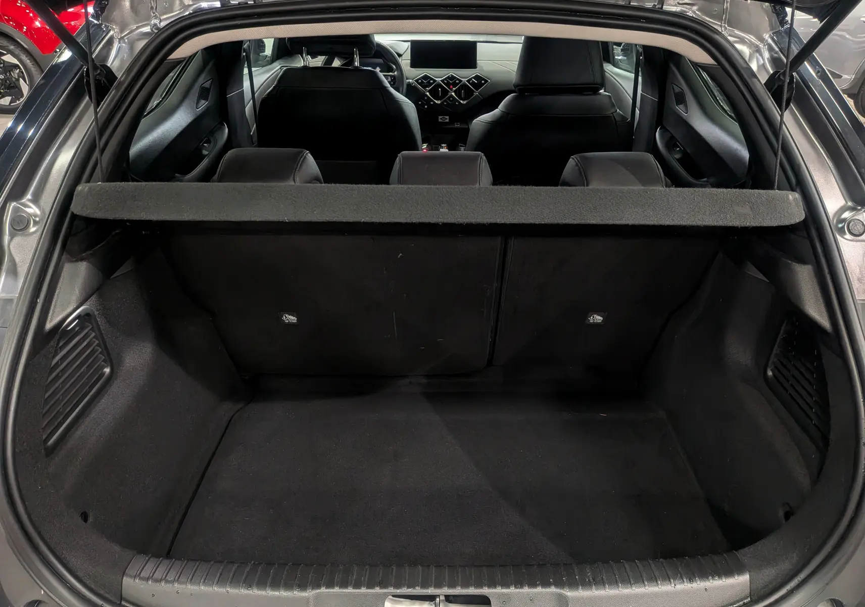 Coffre ouvert vu de l'arrière d'un DS3 Crossback gris Platinium avec intérieur noir et tablette cache-bagages.