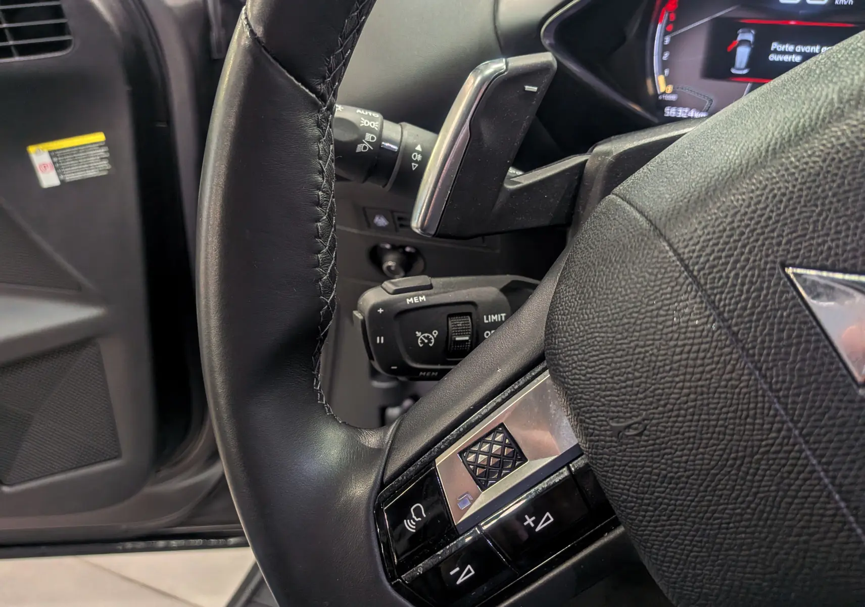 Gros plan sur le volant en cuir noir du DS3 Crossback 2022 avec commandes intégrées et tableau de bord partiellement visible.