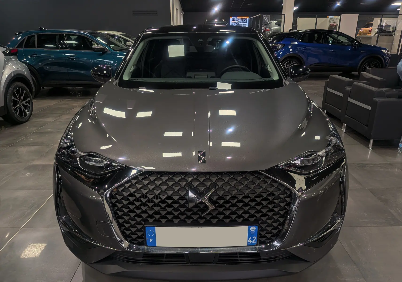 Vue frontale d'un DS3 Crossback gris Platinium avec toit noir, mettant en valeur sa calandre distinctive et ses phares LED.