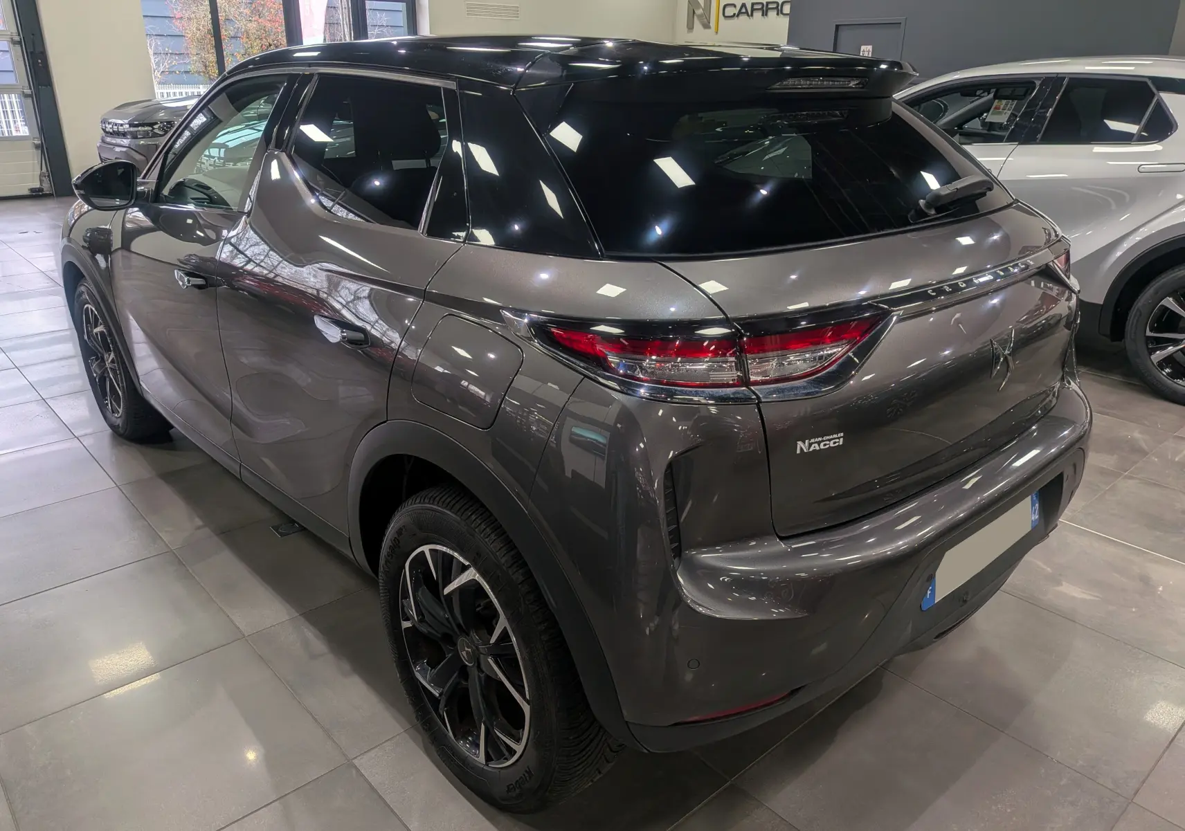 Vue 3/4 arrière droite d'un DS3 Crossback gris Platinium avec toit noir, jantes noires et feux arrière LED distinctifs.