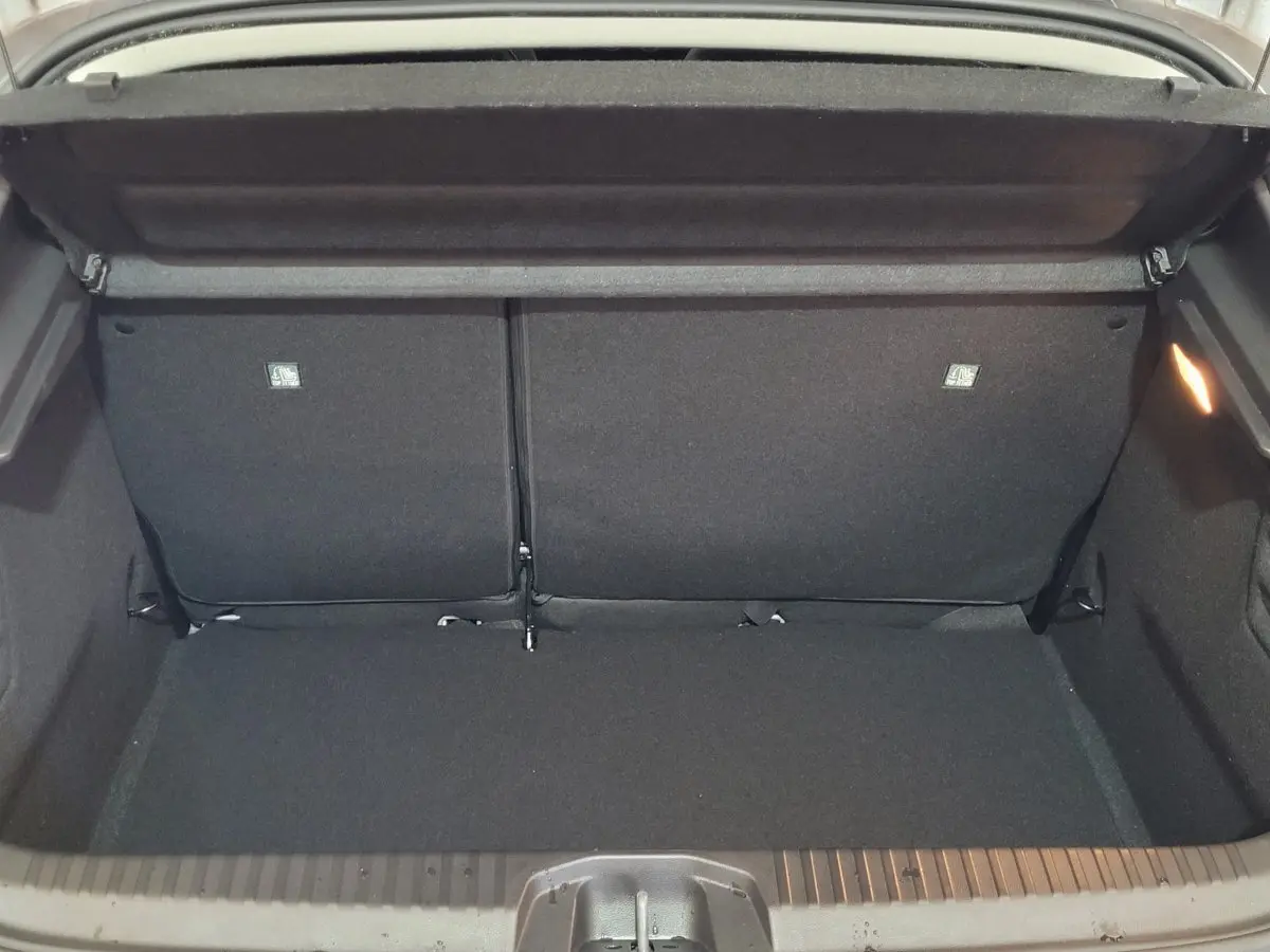 Coffre ouvert vu de l'arrière d'une Renault Clio gris foncé, montrant l'espace de chargement et la banquette arrière rabattue.