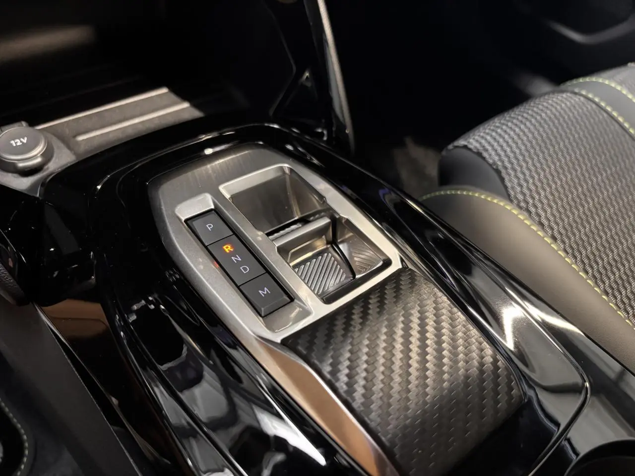 Gros plan sur la console centrale du Peugeot 2008 blanc 2025, mettant en valeur la boîte automatique et les surpiqûres vertes des sièges.