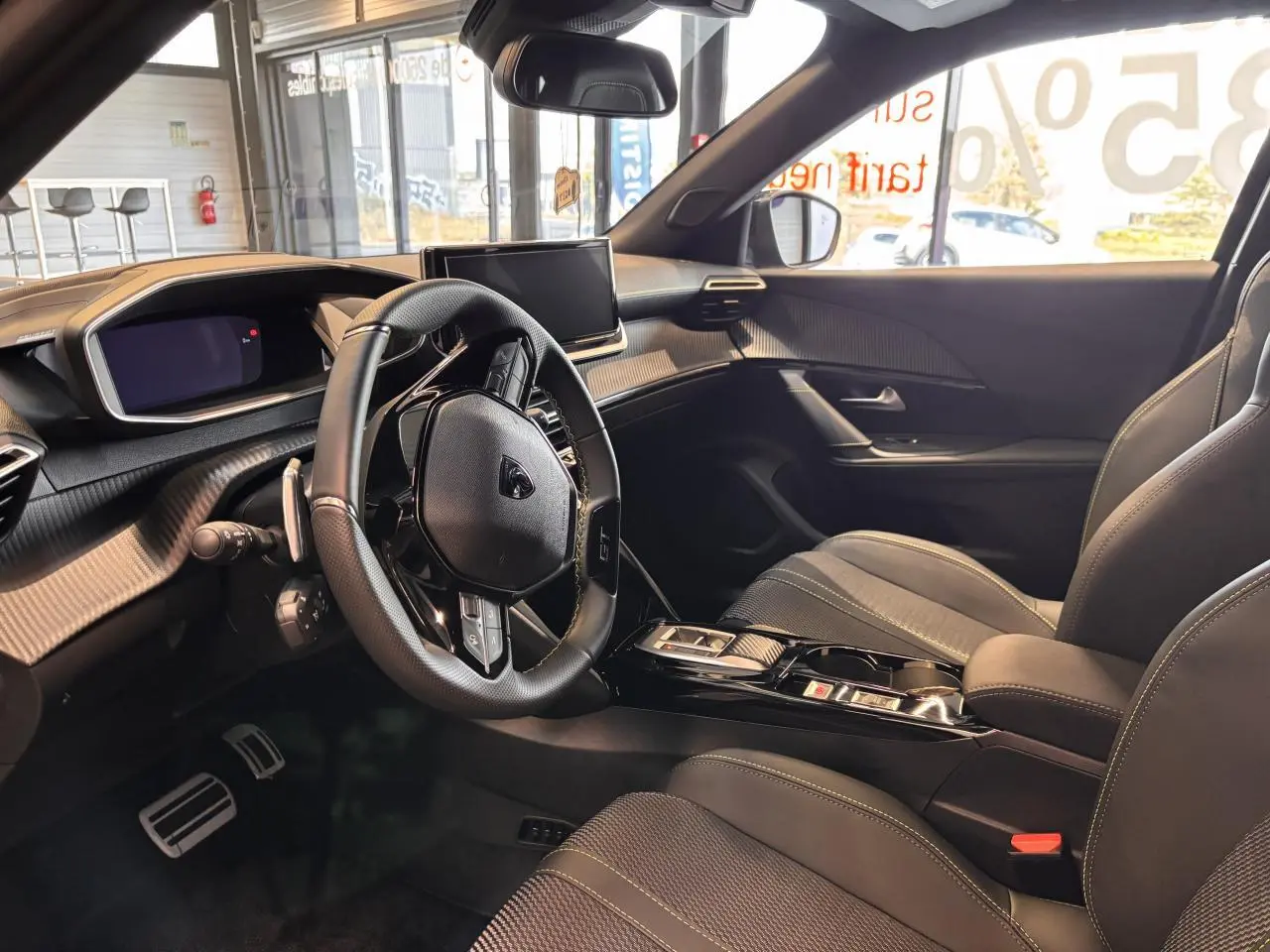 Intérieur noir du Peugeot 2008 hybride 2025 vu côté conducteur, avec volant compact et écran central tactile.
