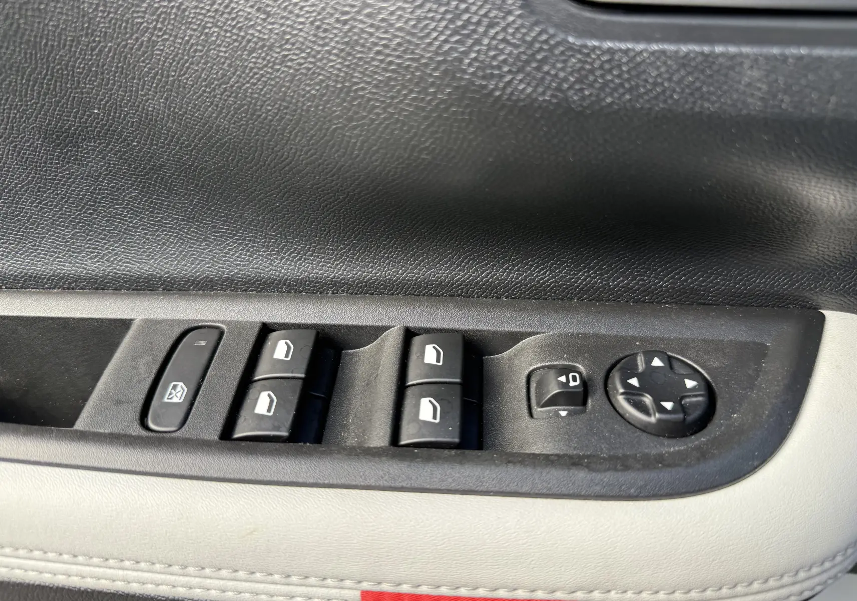 Gros plan sur les commandes de lève-vitres et réglage des rétroviseurs côté conducteur d'une Citroën C3 Aircross gris Mercury toit noir.