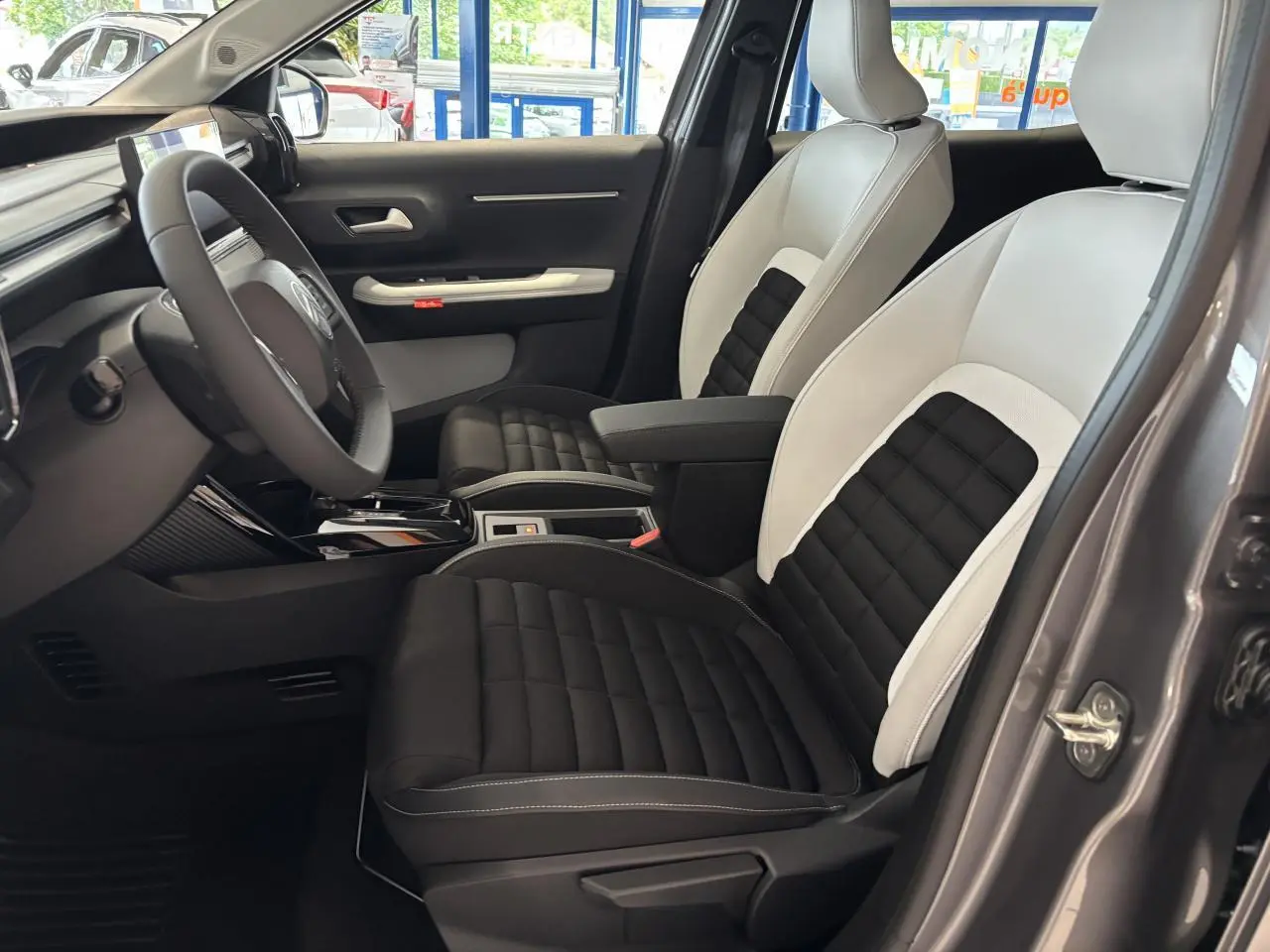 Vue intérieure côté conducteur du Citroën C3 Aircross 2026, sièges bicolores noir et blanc, volant multifonctions.