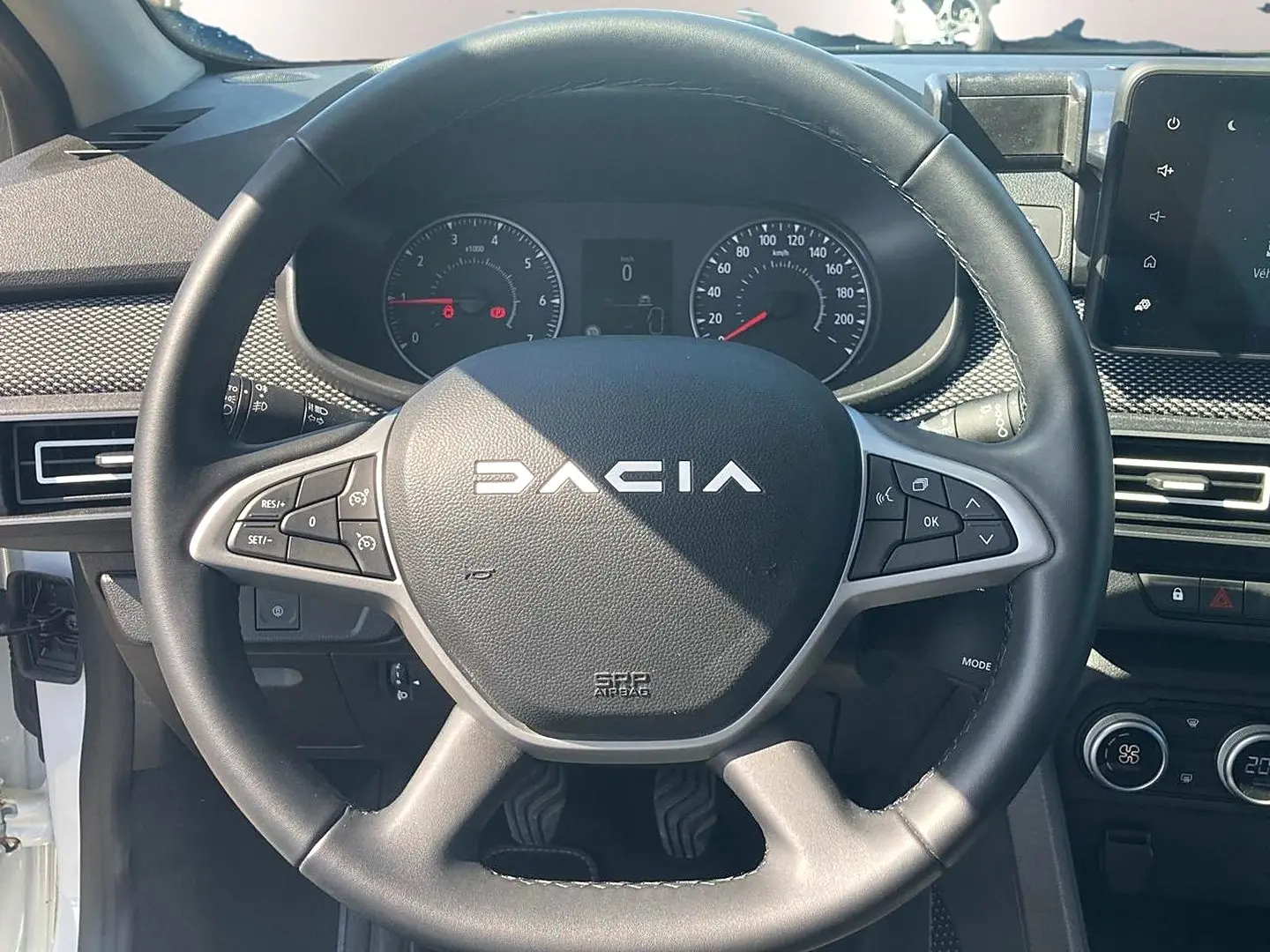 Vue rapprochée du volant noir de la Dacia Sandero 2025 avec commandes intégrées et tableau de bord visible.