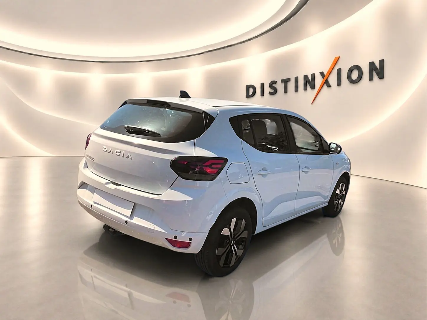 Vue 3/4 arrière droite d'une Dacia Sandero blanche 2025 avec jantes alu et feux arrière LED noirs.