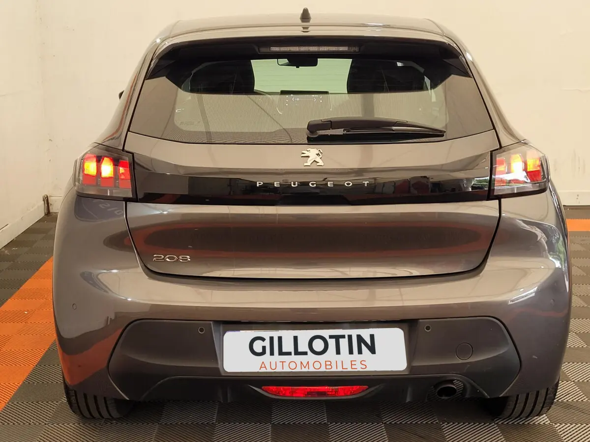 Vue arrière d'une Peugeot 208 gris foncé 2023 avec feux arrière allumés et logo Peugeot visible.