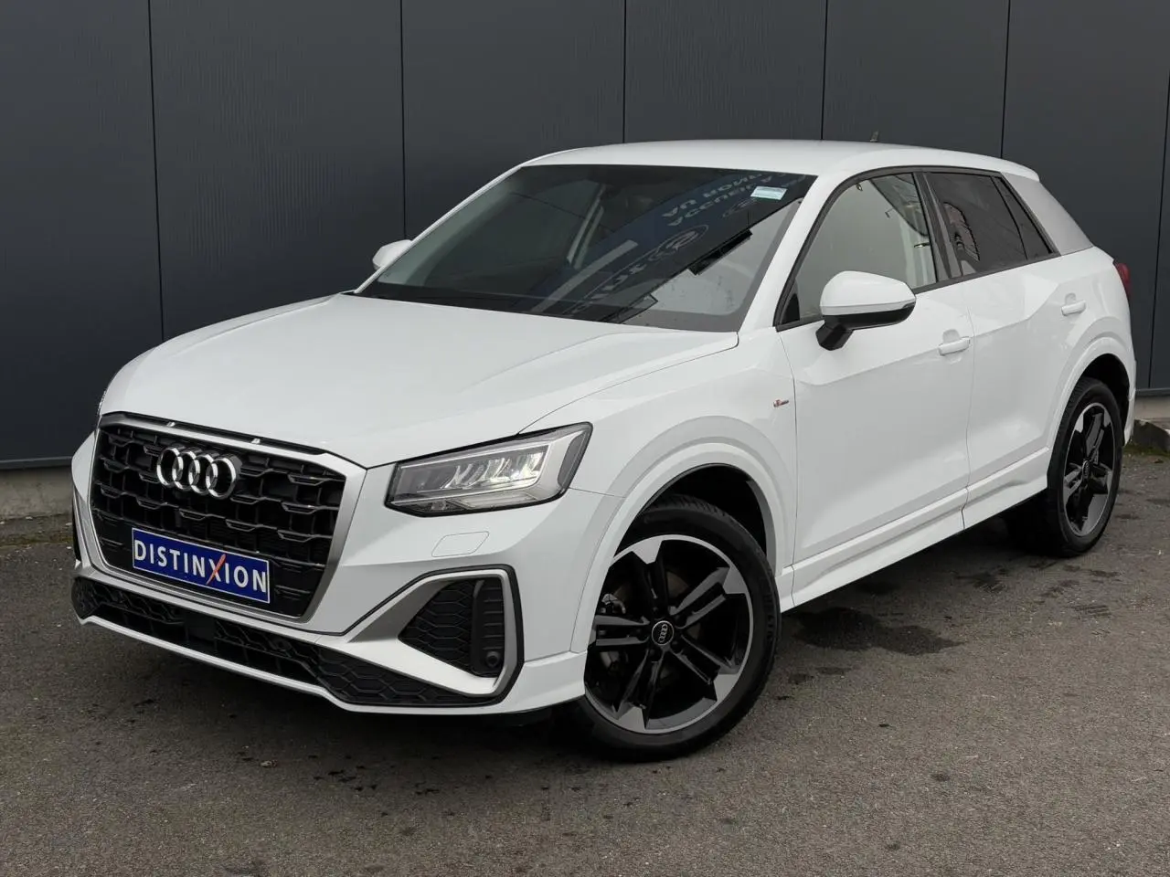 Audi Q2 30 TFSI S-Line blanc Glacier en 3/4 avant droit avec jantes alliage noir poli et vitres surteintées.