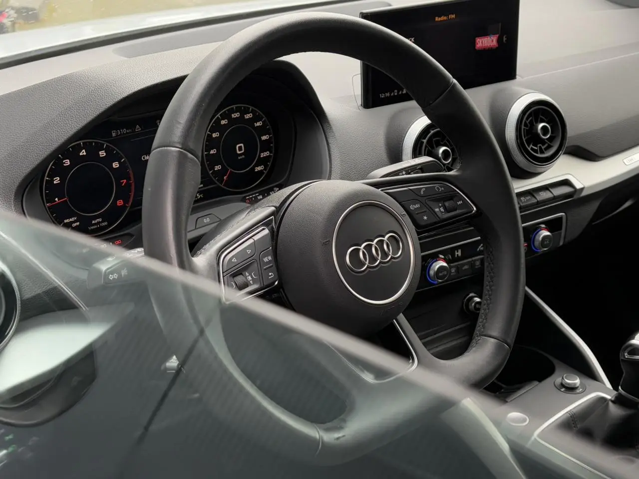 Vue intérieure rapprochée du volant cuir multifonction et du tableau de bord numérique de l'Audi Q2 30 TFSI S-Line 2024.