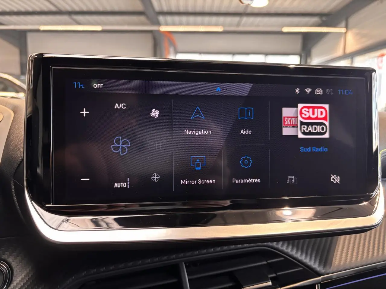 Écran tactile central du tableau de bord du Peugeot 2008 gris, affichant les options de navigation et climatisation.