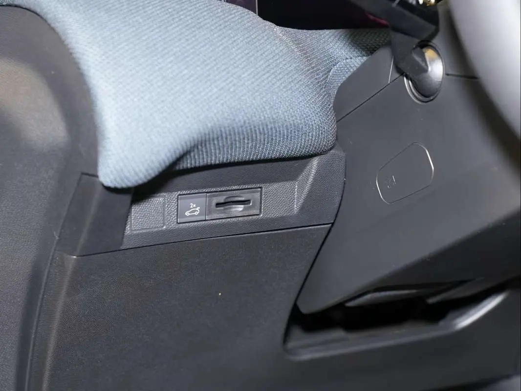 Détail intérieur montrant le bouton d'ouverture du hayon sous le tableau de bord côté conducteur du Citroën C5 Aircross blanc.