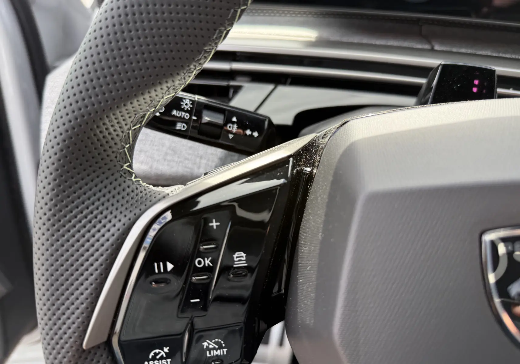 Gros plan sur le volant perforé noir et les commandes intégrées du Peugeot 3008 Hybrid 2026, intérieur moderne.