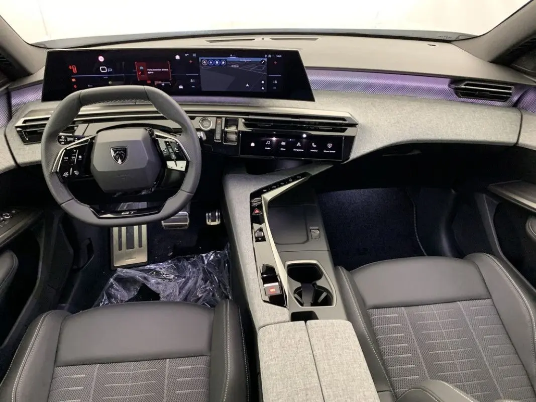 Vue intérieure avant du Peugeot 3008 Hybrid 2026, tableau de bord numérique large et sellerie cuir noire avec console centrale grise.