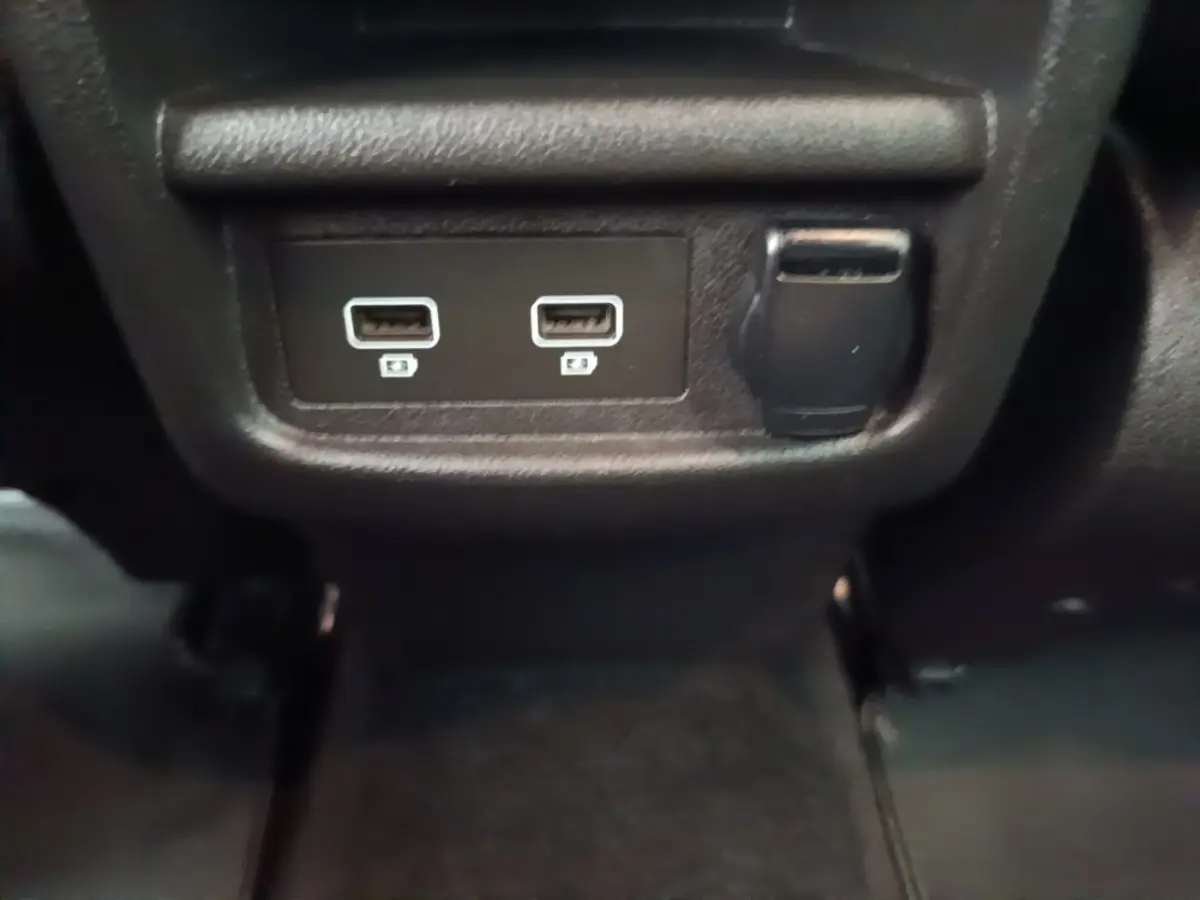 Prise USB double et prise 12V noire en gros plan à l'arrière du Renault Kadjar Business Blue dCi 115 EDC 2021 gris foncé.