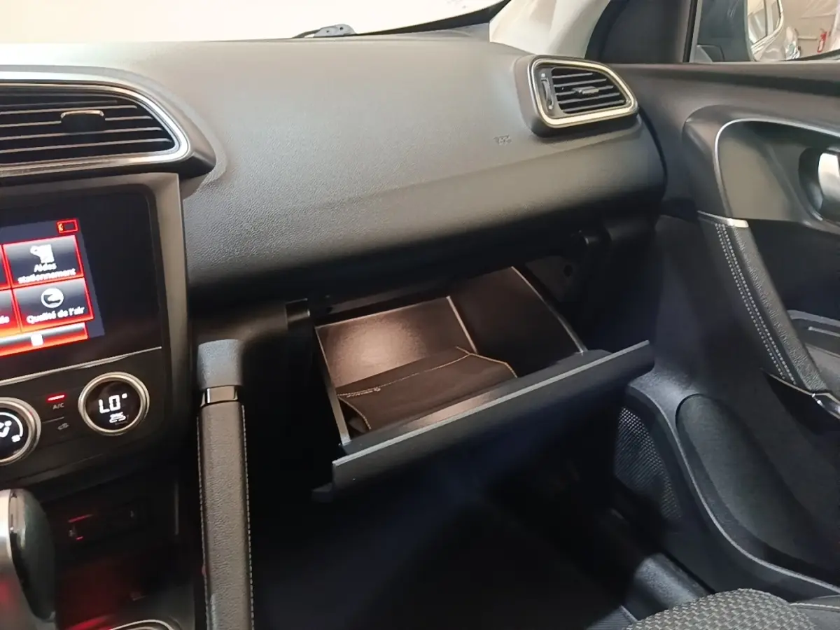 Intérieur du Renault Kadjar Business 2021, vue côté passager sur boîte à gants ouverte et tableau de bord noir.