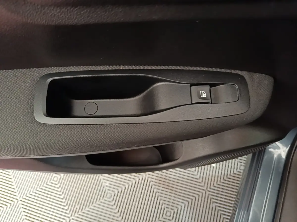Détail de la commande de lève-vitre côté conducteur sur la porte intérieure du Renault Kadjar gris foncé.