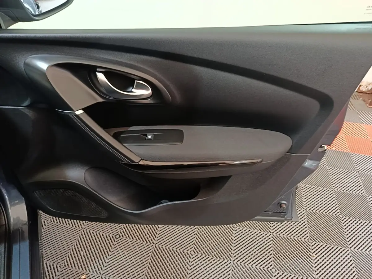 Vue rapprochée de la porte avant gauche gris foncé du Renault Kadjar 2021 avec poignée intérieure et commande de vitre.