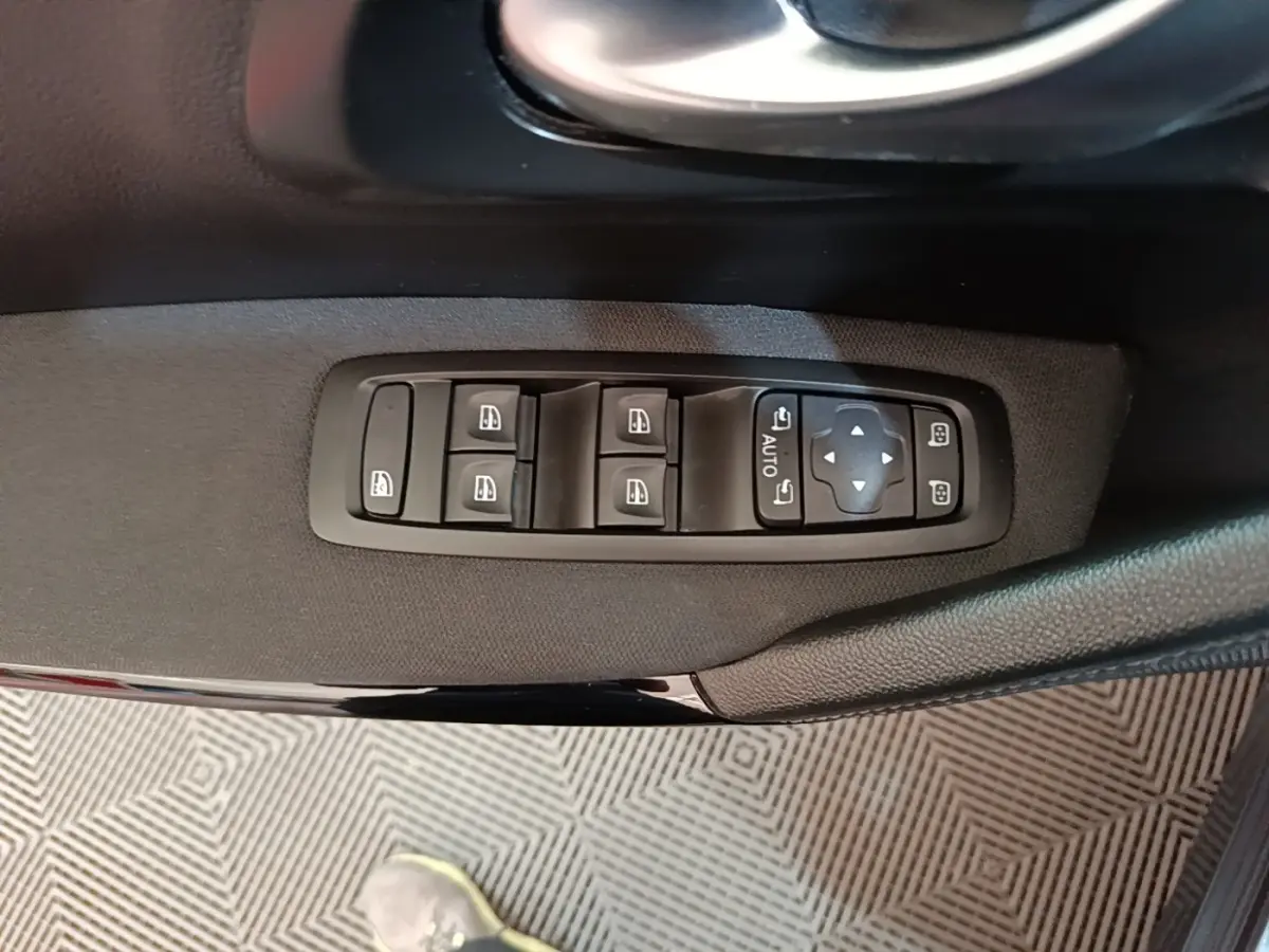 Gros plan sur les commandes électriques des vitres et des rétroviseurs côté conducteur d’une Renault Kadjar gris foncé.