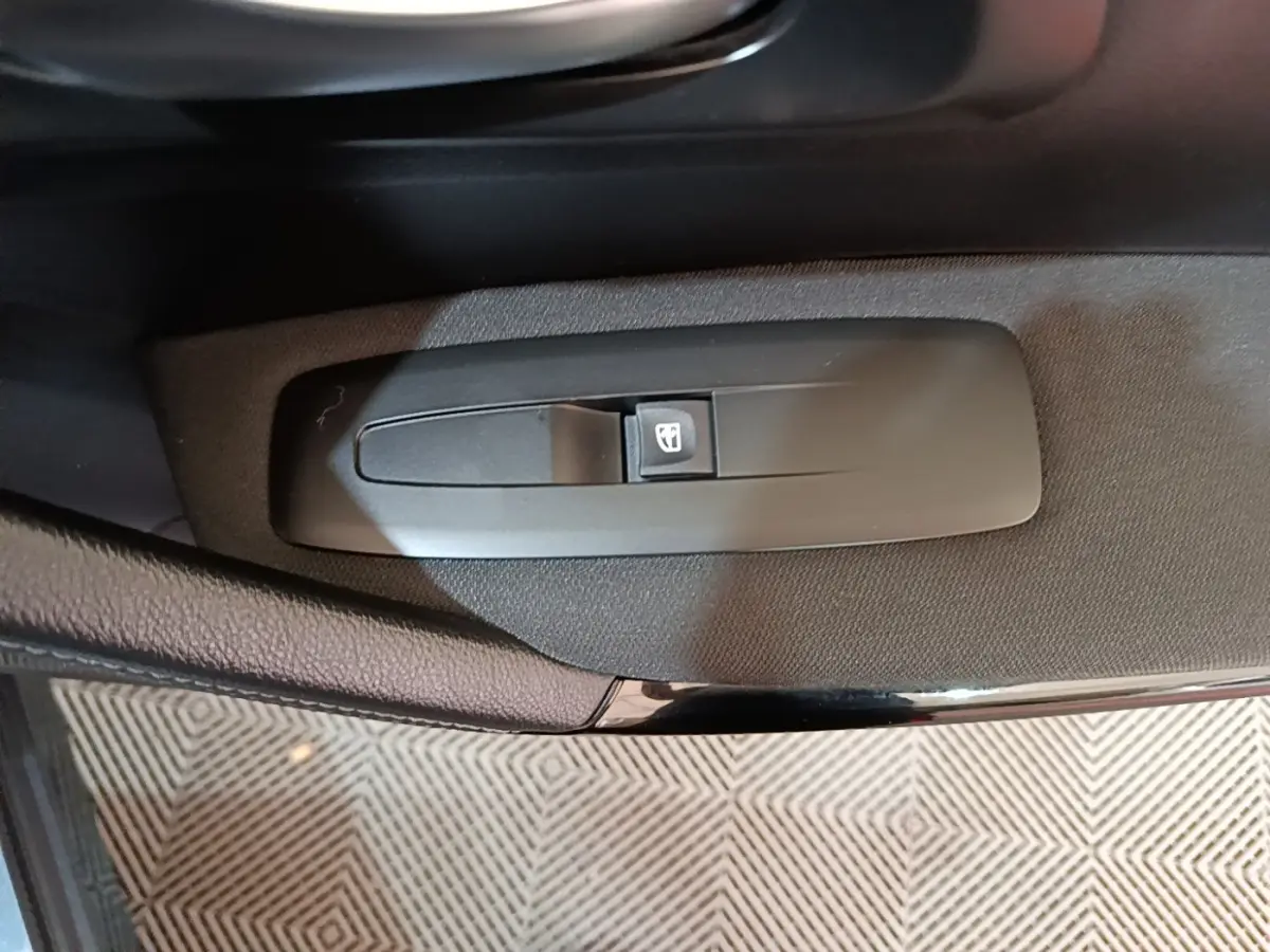 Gros plan sur le bouton de commande de la vitre électrique côté conducteur du Renault Kadjar gris foncé.