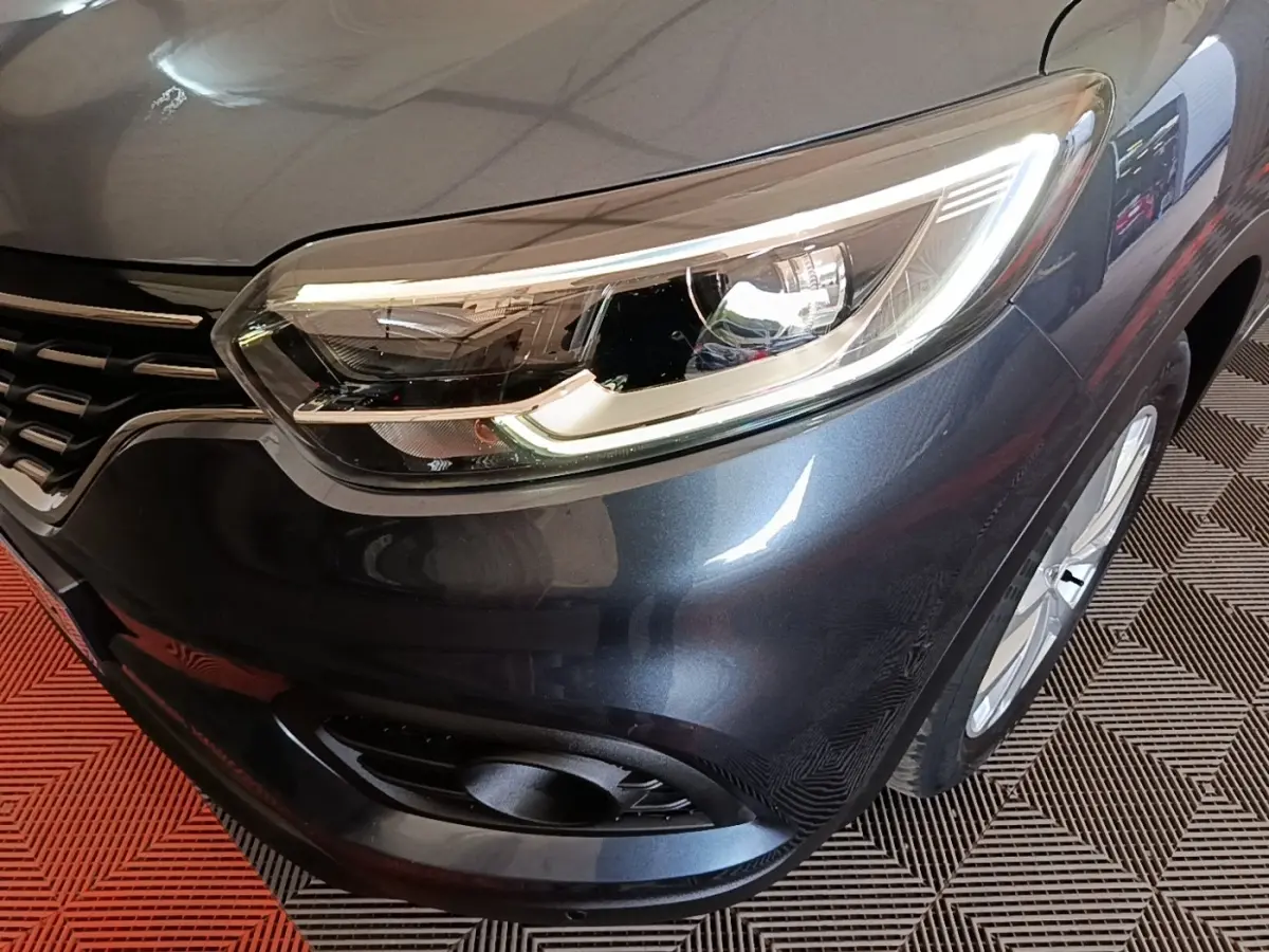 Gros plan sur l'avant droit du Renault Kadjar gris foncé, mettant en valeur le phare LED et la calandre.