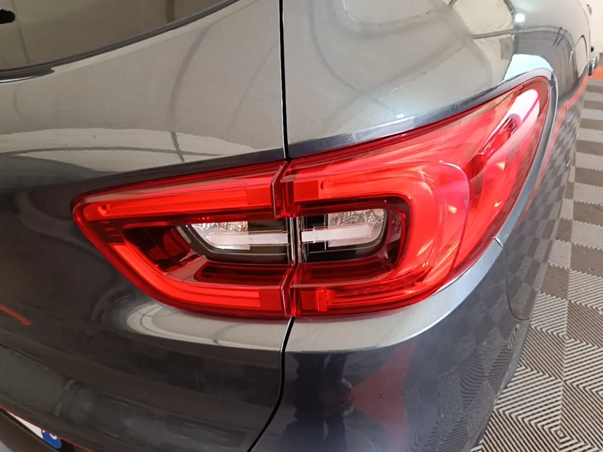 Gros plan sur le feu arrière droit rouge d’un Renault Kadjar gris foncé, avec reflet sur la carrosserie lisse.