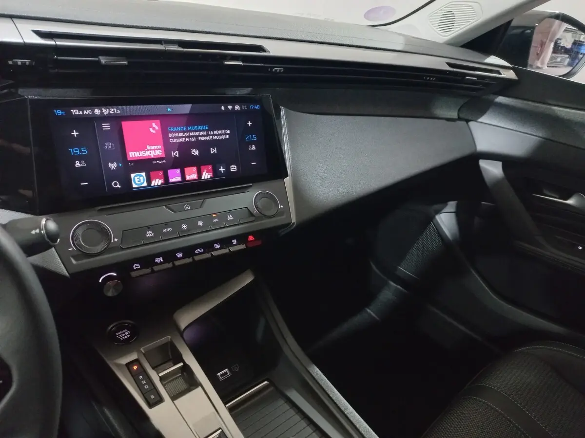 Vue intérieure côté passager de la Peugeot 308 PHEV 180 E-EAT8 Allure 2025, avec écran tactile central et console moderne.