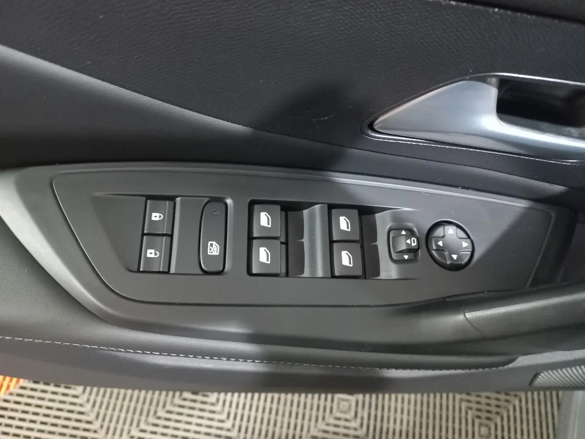 Gros plan sur la commande des vitres et rétroviseurs côté conducteur de la Peugeot 308 PHEV 180 Allure gris foncé.