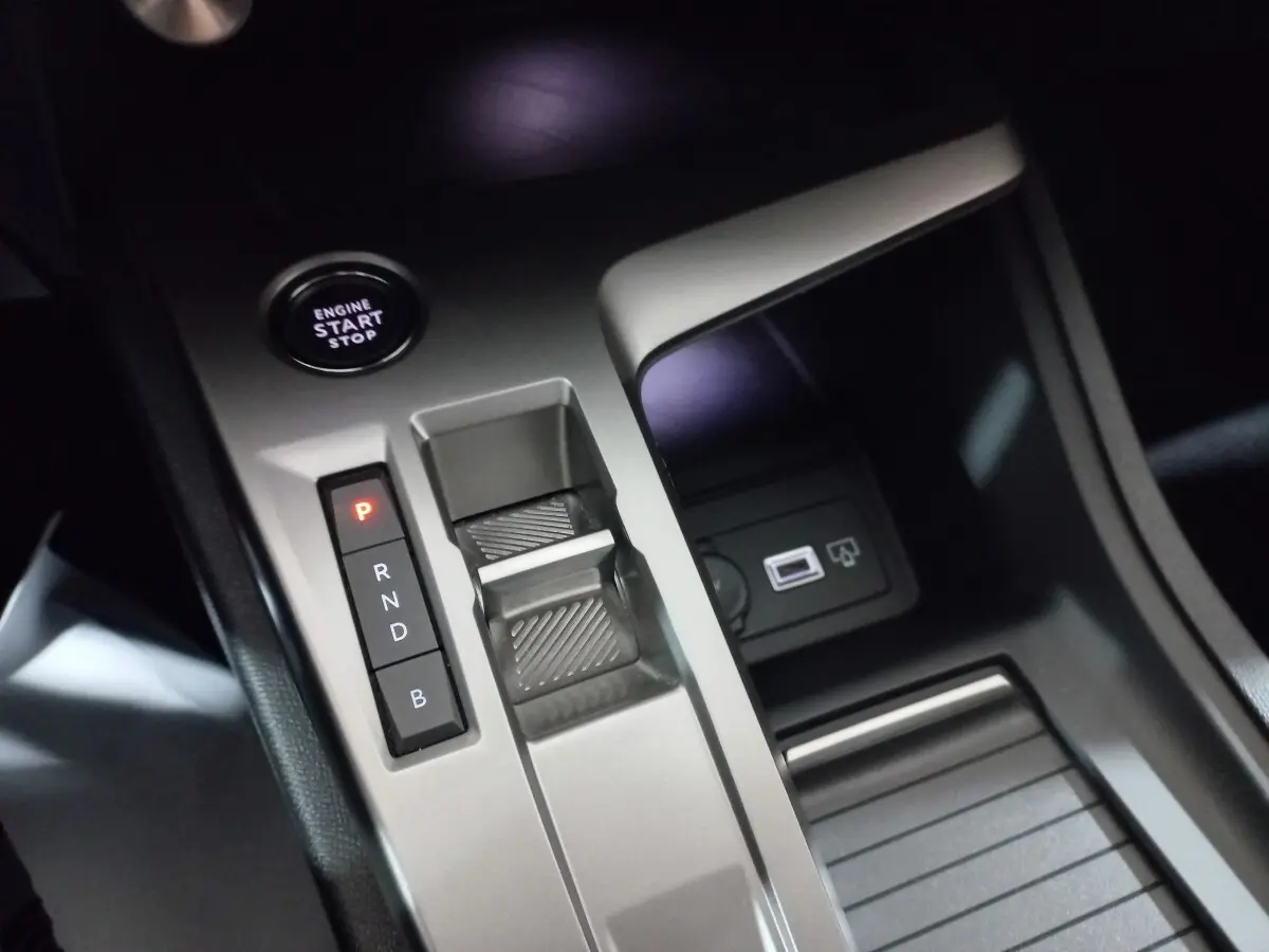 Gros plan sur la console centrale grise de la Peugeot 308 PHEV 180 E-EAT8 Allure avec bouton start et sélecteur de boîte auto.