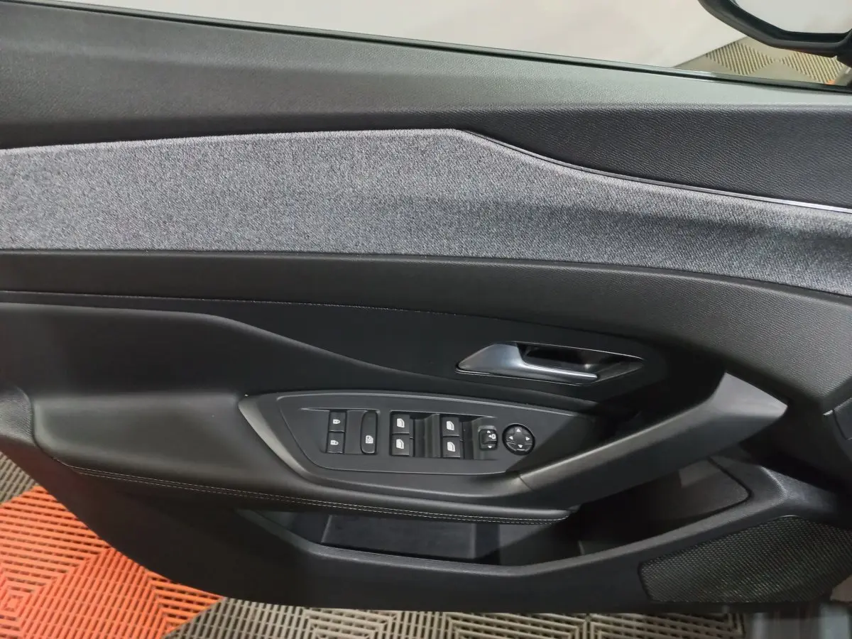 Gros plan sur la porte intérieure côté conducteur de la Peugeot 308 PHEV 180 Allure avec commandes de vitres et revêtement gris foncé.