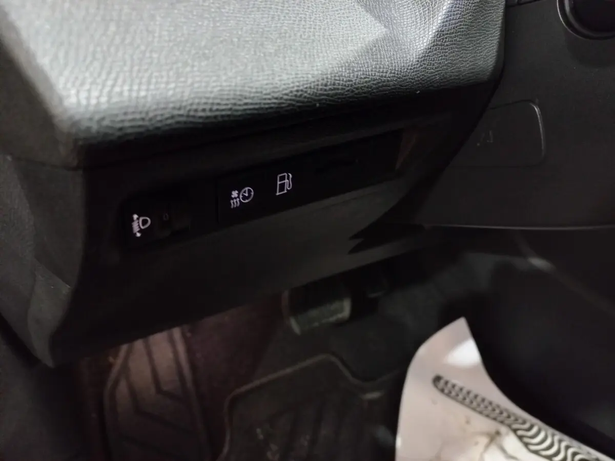 Détail intérieur côté conducteur de la Peugeot 308 PHEV 2025 montrant les commandes d’éclairage et de carburant sous le tableau de bord noir.