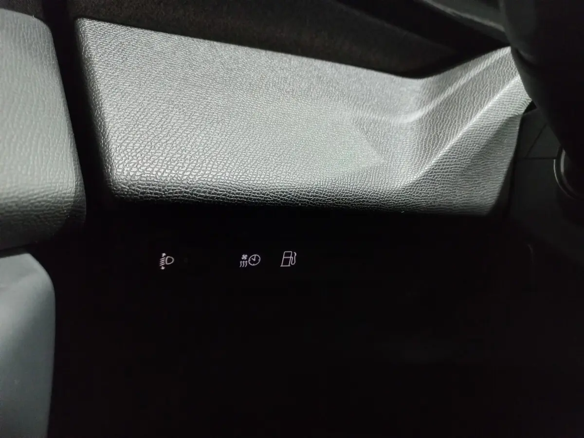 Gros plan sur la partie inférieure du tableau de bord gris texturé avec voyants lumineux blancs dans l'habitacle Peugeot 308 PHEV.