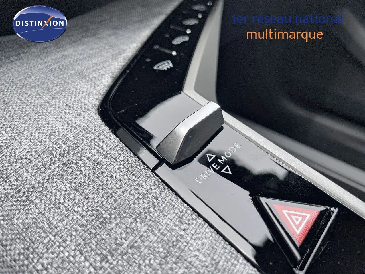 Gros plan sur la commande Drive Mode et bouton de signalisation d'urgence du Peugeot 5008 hybride gris titane intérieur tissu gris.