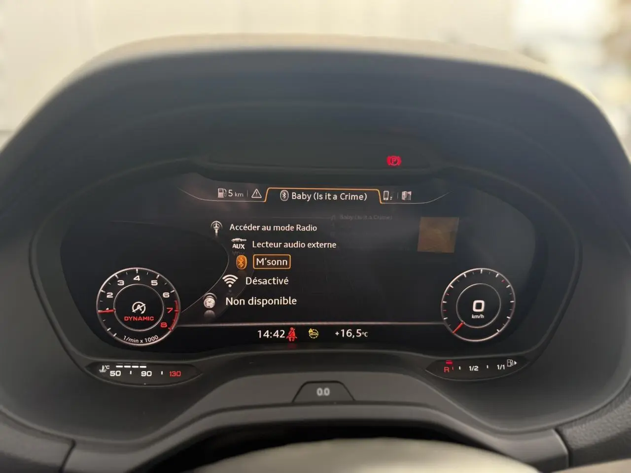 Vue rapprochée du tableau de bord numérique Audi virtual cockpit affichant les informations audio et la température extérieure.
