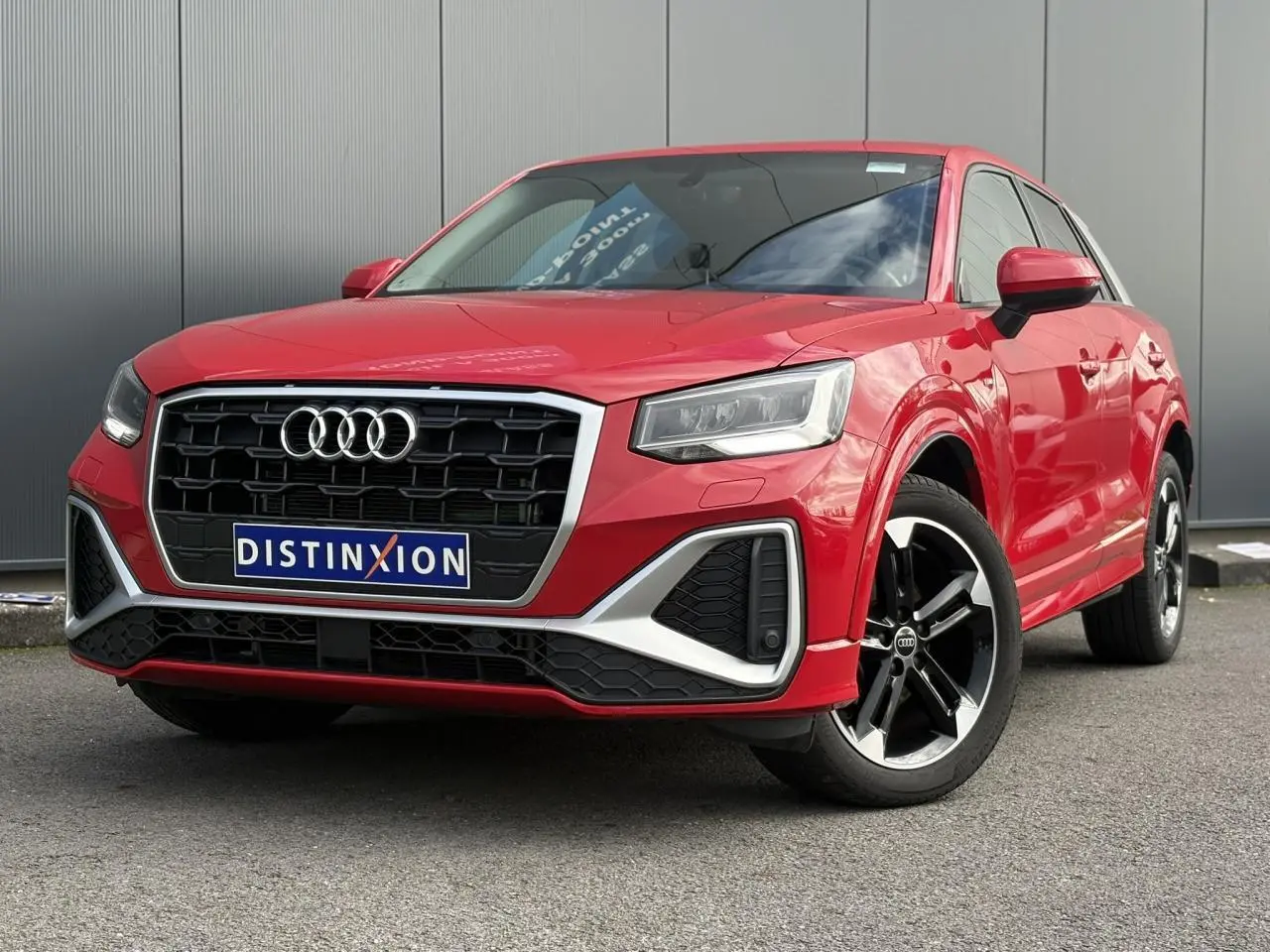 Audi Q2 30 TFSI S-Line rouge Progressif en 3/4 avant droit, avec calandre noire et jantes alliage 5 branches doubles.