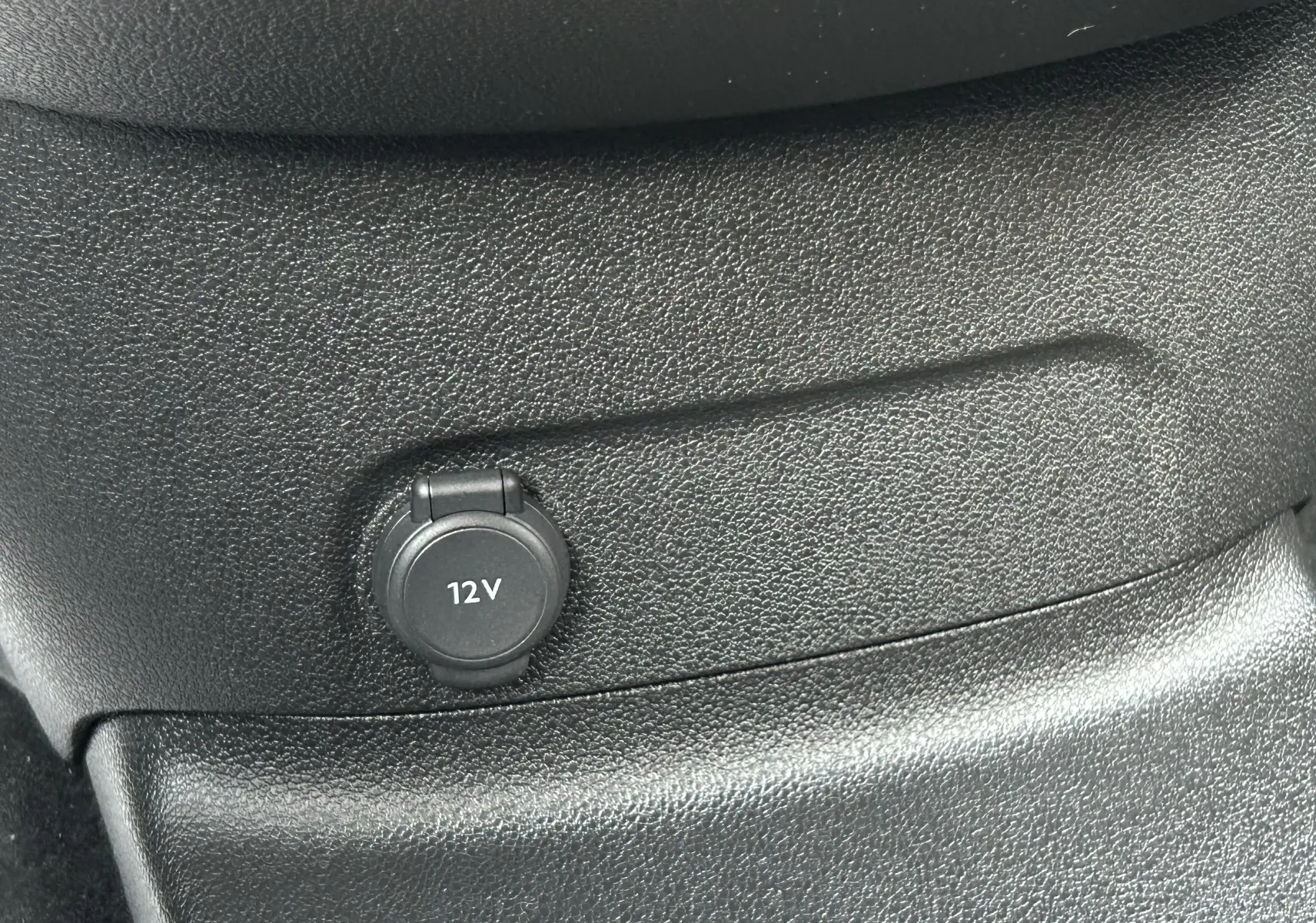 Prise 12V en gros plan sur la console intérieure noire du Peugeot Partner Fourgon blanc 2025.