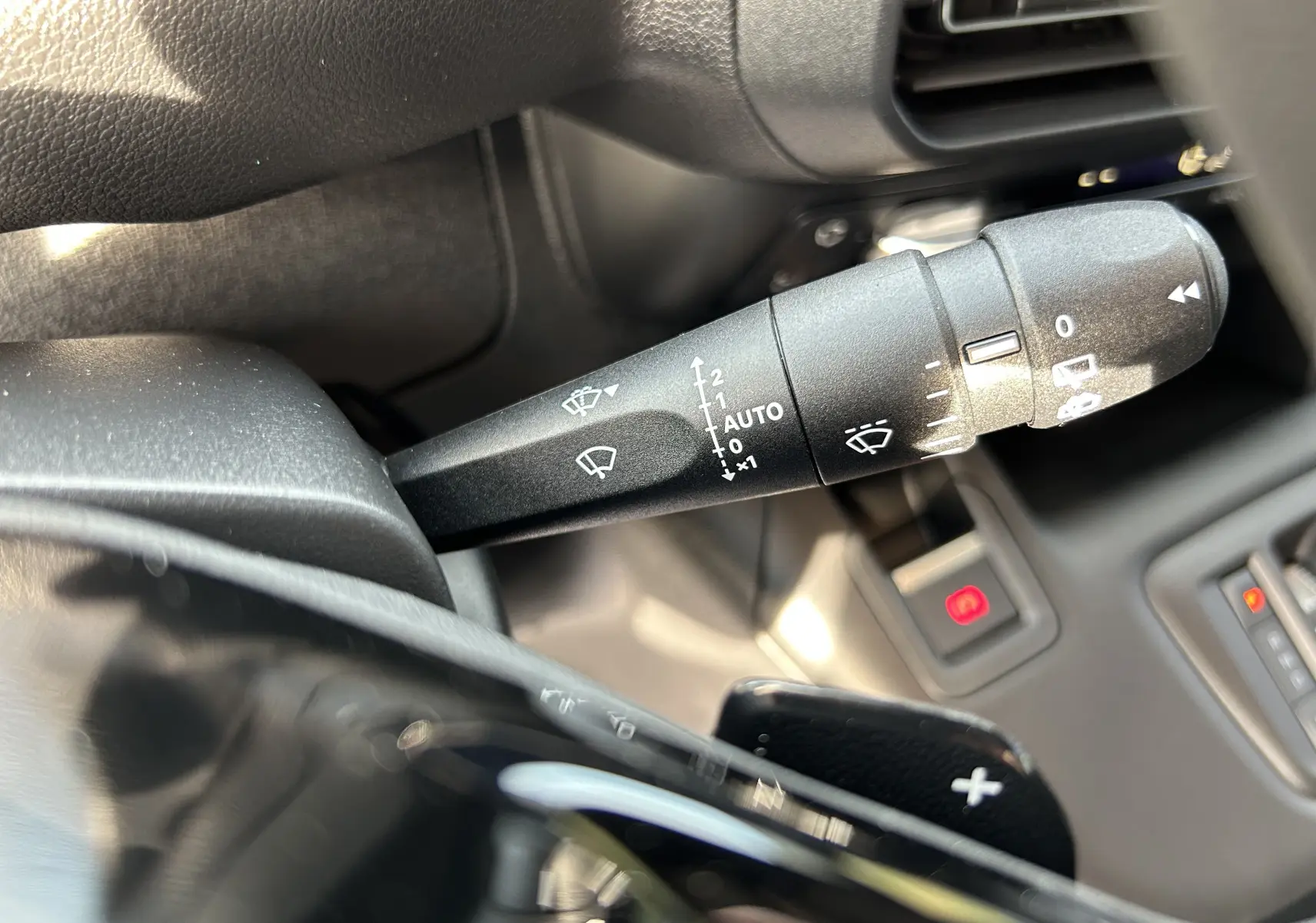 Gros plan sur la commande d'essuie-glace du Peugeot Partner Fourgon 2025, intérieur noir avec palettes au volant.