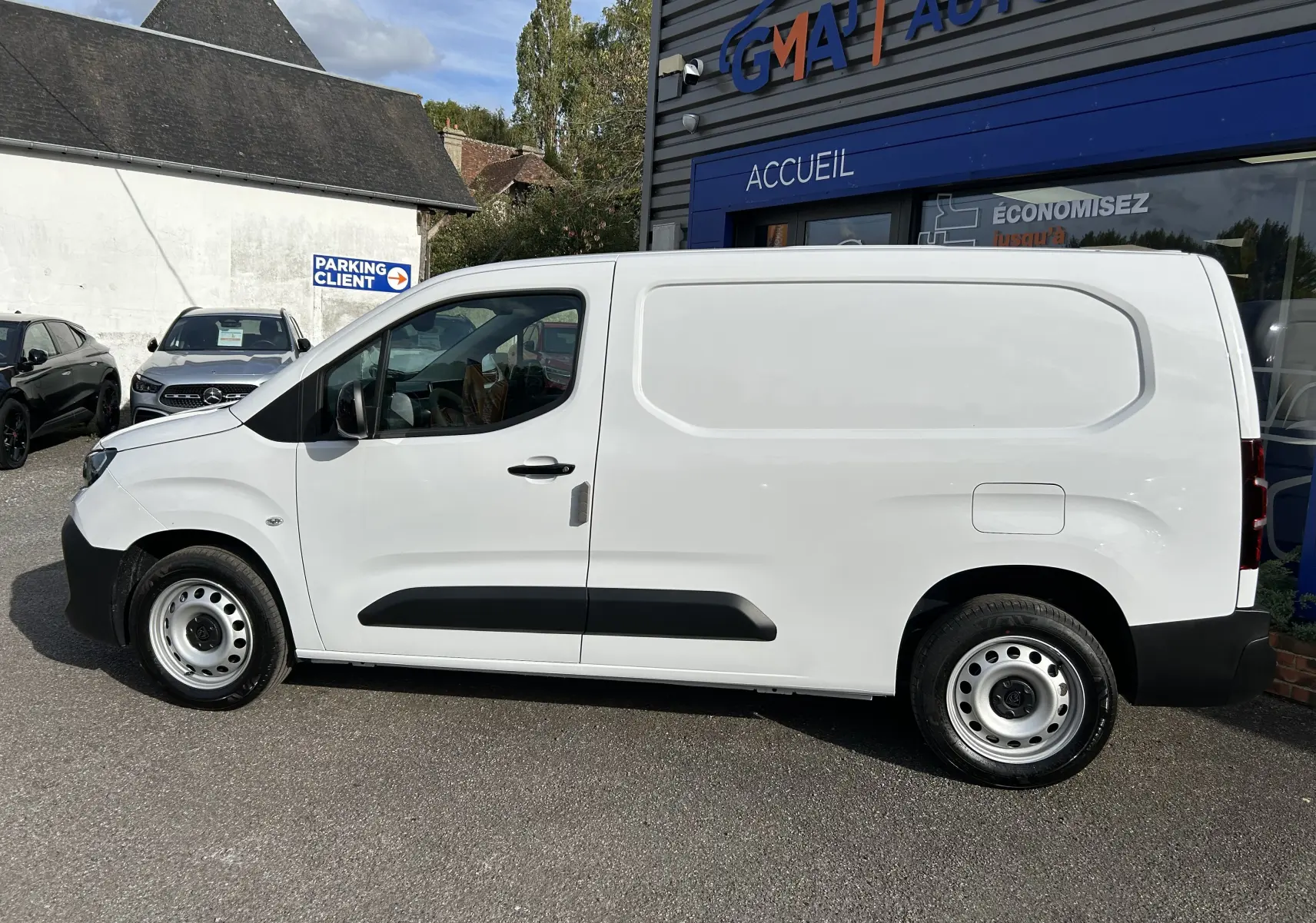 Profil droit d'un utilitaire blanc Peugeot Partner Fourgon 2025 avec plancher bois visible sur le côté et jantes acier.