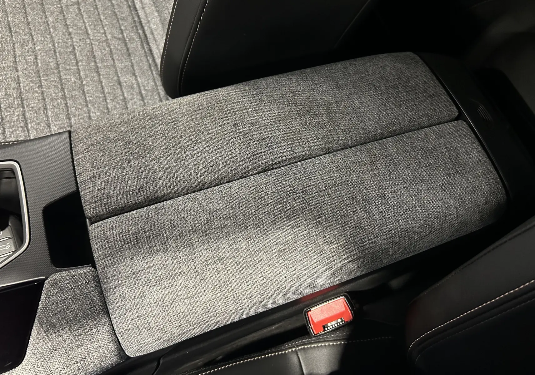 Détail de l'accoudoir central en tissu gris dans l'habitacle du Peugeot 5008 III Hybrid 145 e-DCS6 Allure.