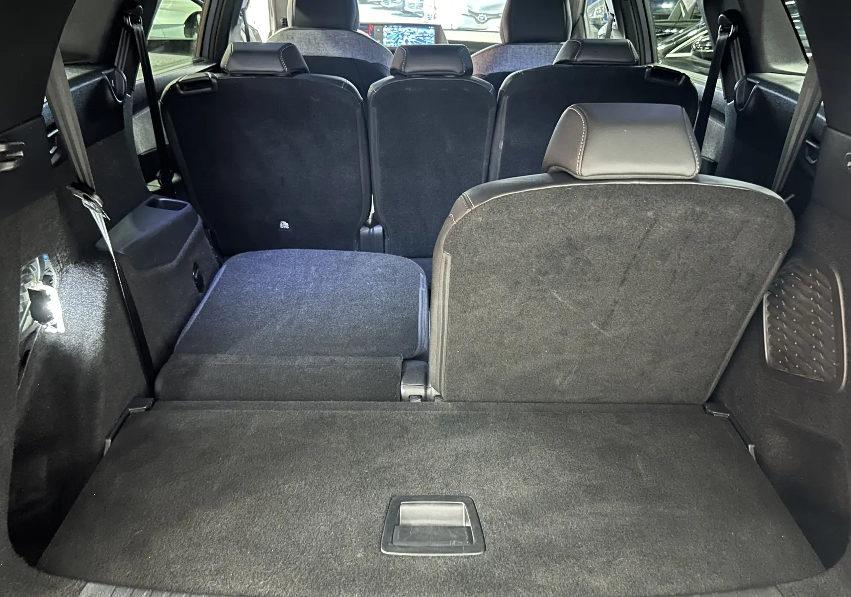 Vue arrière intérieure du coffre du Peugeot 5008 gris Artense, sièges arrière partiellement rabattus pour augmenter l'espace de chargement.