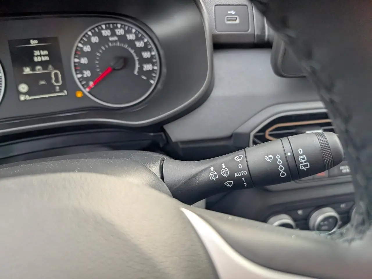 Gros plan sur la commande d'essuie-glace à droite du volant dans le tableau de bord gris du Dacia Jogger vert métallisé 2025.