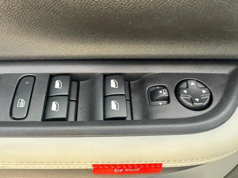 Gros plan sur les commandes de lève-vitres et réglage des rétroviseurs côté conducteur du Citroën C3 Aircross gris Mercury.