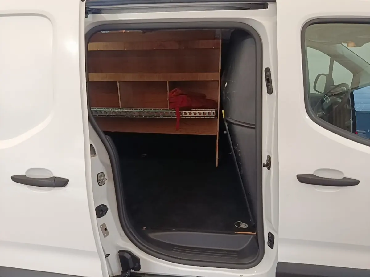 Vue latérale gauche d’un Citroën Berlingo blanc 2020 avec porte coulissante ouverte montrant l’espace de chargement aménagé.