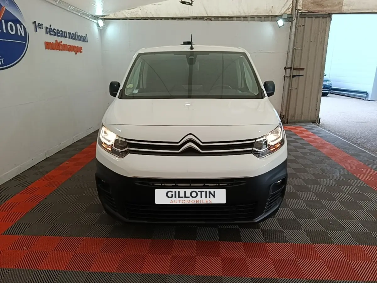 Vue frontale d'un Citroën Berlingo blanc avec phares allumés, calandre noire et plaque d'immatriculation GILLOTIN.