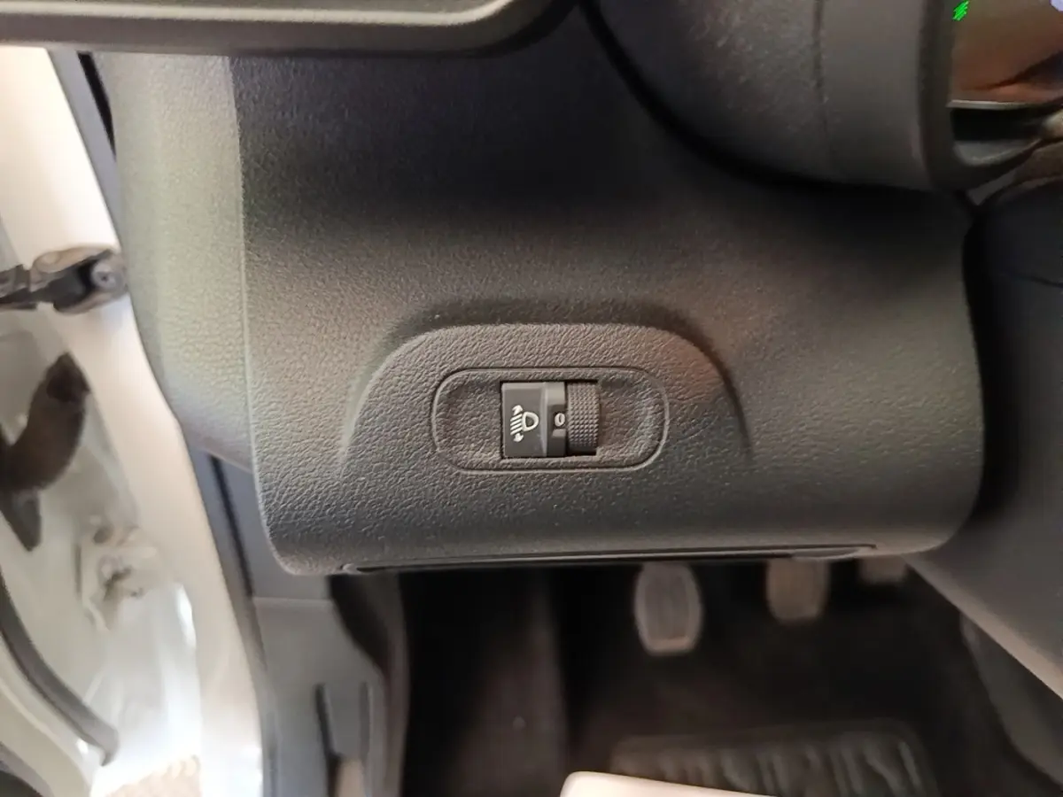 Gros plan sur le réglage manuel de hauteur des phares côté gauche dans un Citroën Berlingo blanc de 2020.