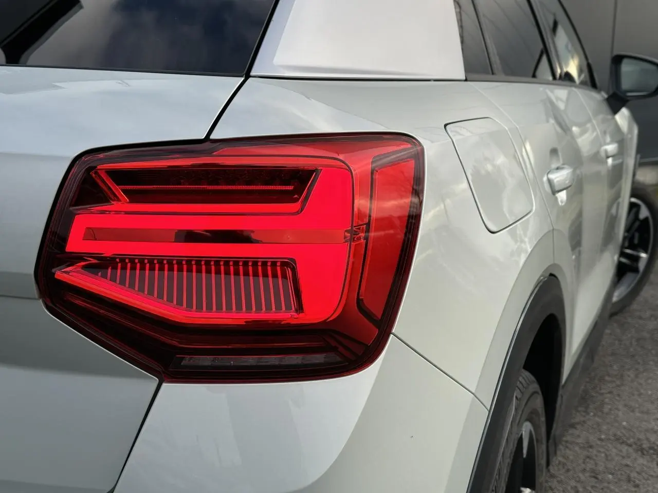 Gros plan sur le feu arrière droit d’un Audi Q2 30 TFSI S-Line argent rosé avec jante noire et détails noirs.