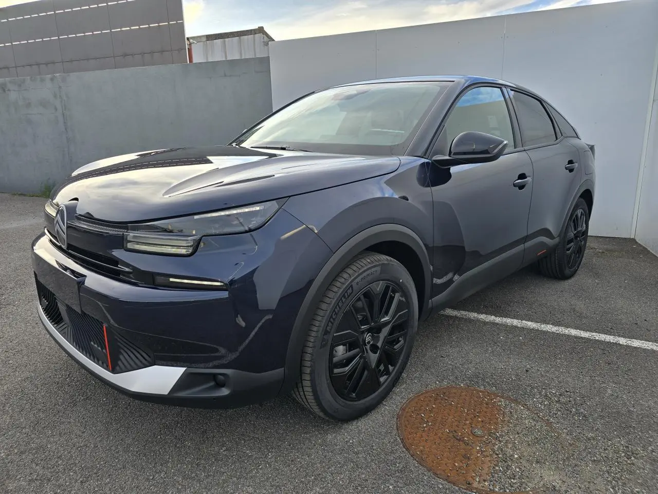 Citroën C4 III hybride bleu eclipse avec toit noir, vue 3/4 avant droit, jantes alliage noires et feux LED distinctifs.